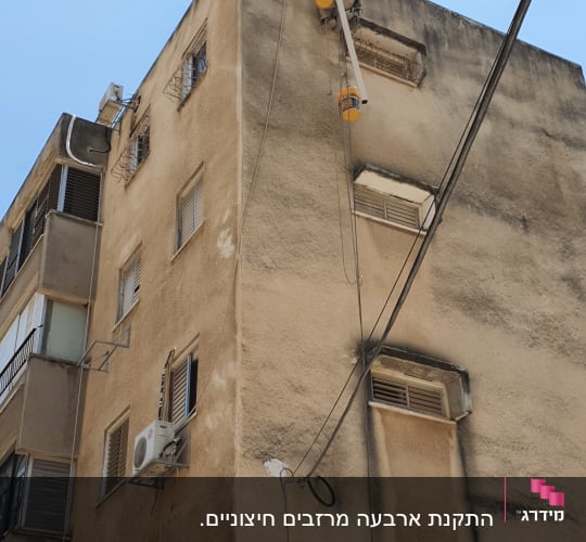 אדם על סולם מתקין מזגן על קיר חיצוני